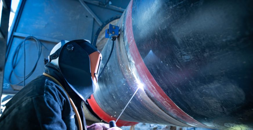 Professional welder welding pipe on a pipeline construction.